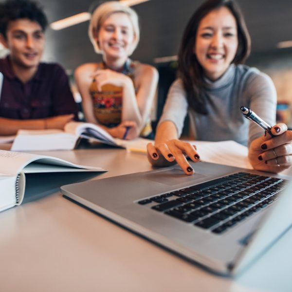 Group of happy friends working on laptop in class