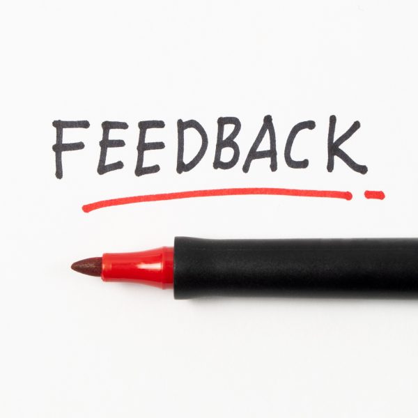 Hand writing Feedback with black and red marker on white paper